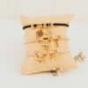 Pulsera chapada oro 24k con medalla grabada mamá y charms circonita sobre cojín beige, joya personalizada Día de la Madre inloff