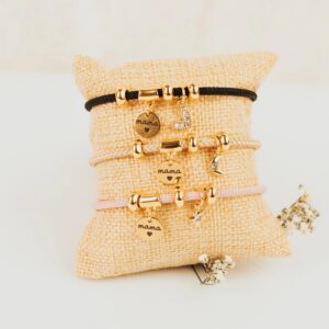 Pulsera chapada oro 24k con medalla grabada mamá y charms circonita sobre cojín beige, joya personalizada Día de la Madre inloff