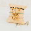 Pulsera oro super mamá personalizada con medalla grabada y charms intercambiables sobre fondo beige