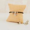 Pulsera de plata personalizada Super Mamá con circonita brillante y medalla grabada, expositora sobre cojín beige con flores secas