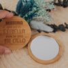 Espejo redondo de bambú personalizado con grabado láser del nombre Marina y frase hoy soy la estrella pero tú eres mi cielo, junto a ramo de flores secas azules sobre fondo natural
