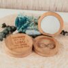 Joyero de bambú personalizado con nombre grabado láser junto a espejo redondo y flores secas azules, mostrando diseño A tu lado para damas de honor de boda