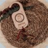 Llave mágica de Papá Noel personalizada en madera natural con nombre grabado, colgador circular y lazo rojo decorativo sobre cesta de mimbre con eucalipto