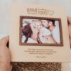 Marco de fotos personalizado de madera para papá con grabado láser, frase Los Abrazos de Papá y dedicatoria personalizada, sostenido en manos sobre fondo claro