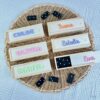 Dominó personalizado de madera con nombres de niños en metacrilato de colores sobre las cajas, presentado sobre cesta artesanal